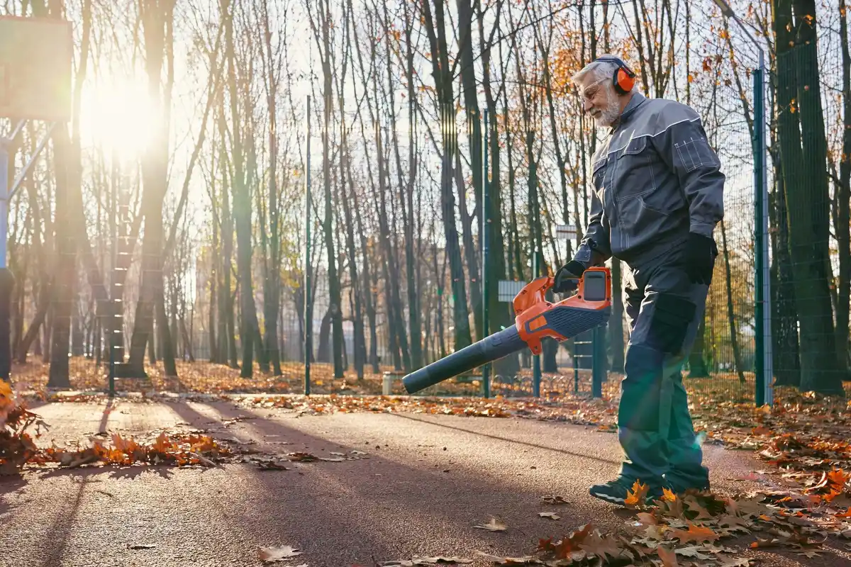 Dutch man cleaning chainsaw in garden shed